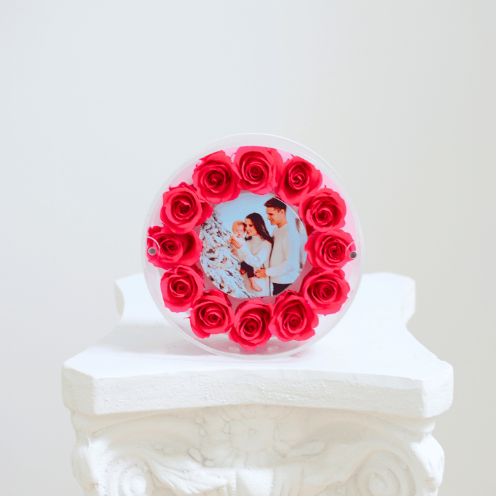 Round photo frame with red roses on a white pedestal